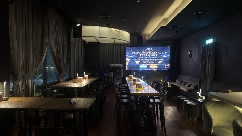Tipsy Plus One event space lounge with communal tables, banquette seating and big screen